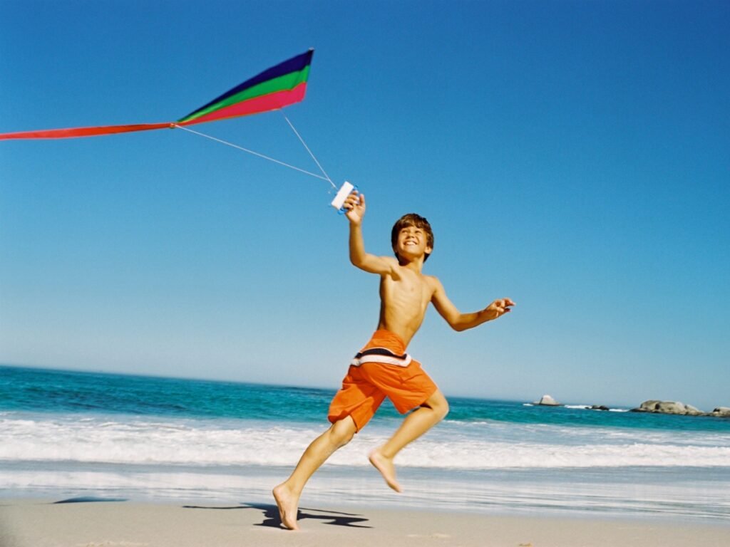 Boy flying a kite Image by BananaStock from Photo Images - Best Beach Activities for Kids