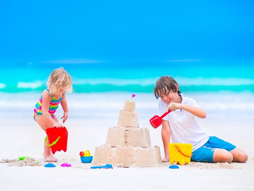 Kids building sand castle on the beach⁠ - Image by FamVeld from Getty Images - Best Beach Activities for Kids