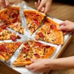 Best Pizza Places in Phoenix, AZ - Group Of Friends Sharing Pizza. Image by puhhha from Getty Images Pro