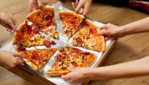 Best Pizza Places in Phoenix, AZ - Group Of Friends Sharing Pizza. Image by puhhha from Getty Images Pro