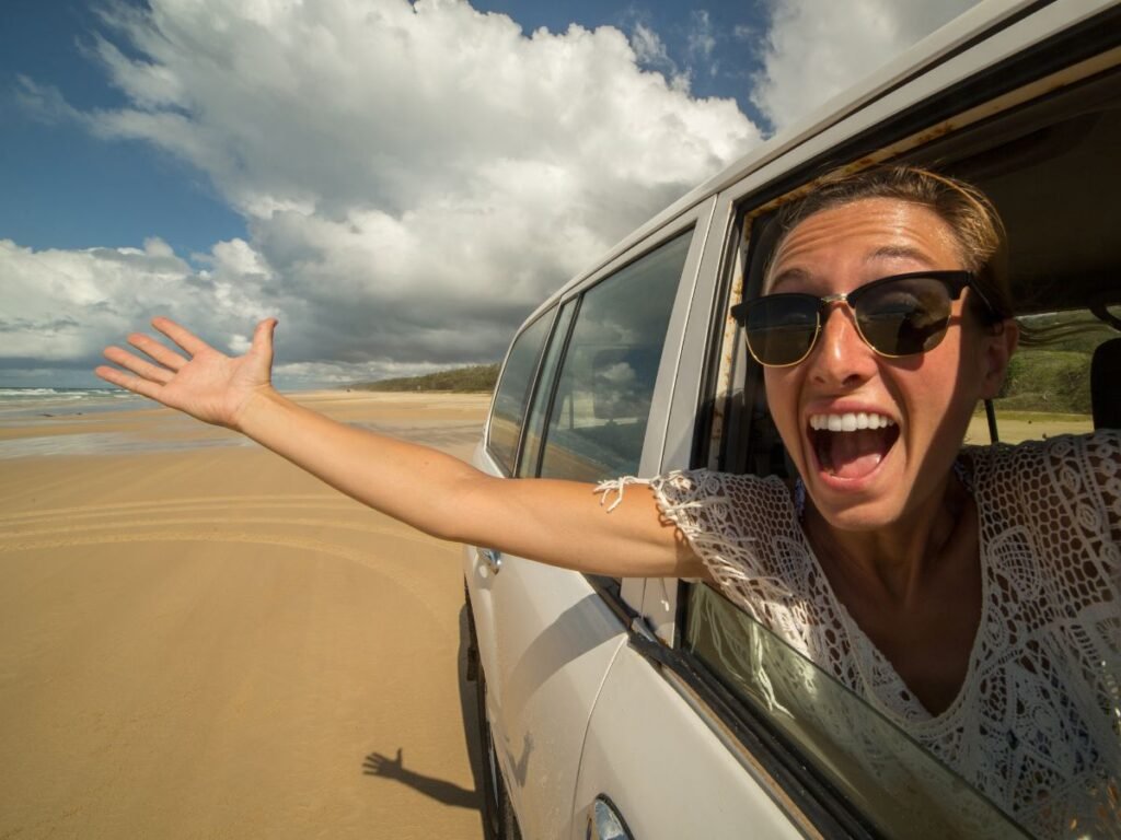 Girl takes selfie while driving a 4x4 on beach Image by swissmediavision from Getty Images Signature