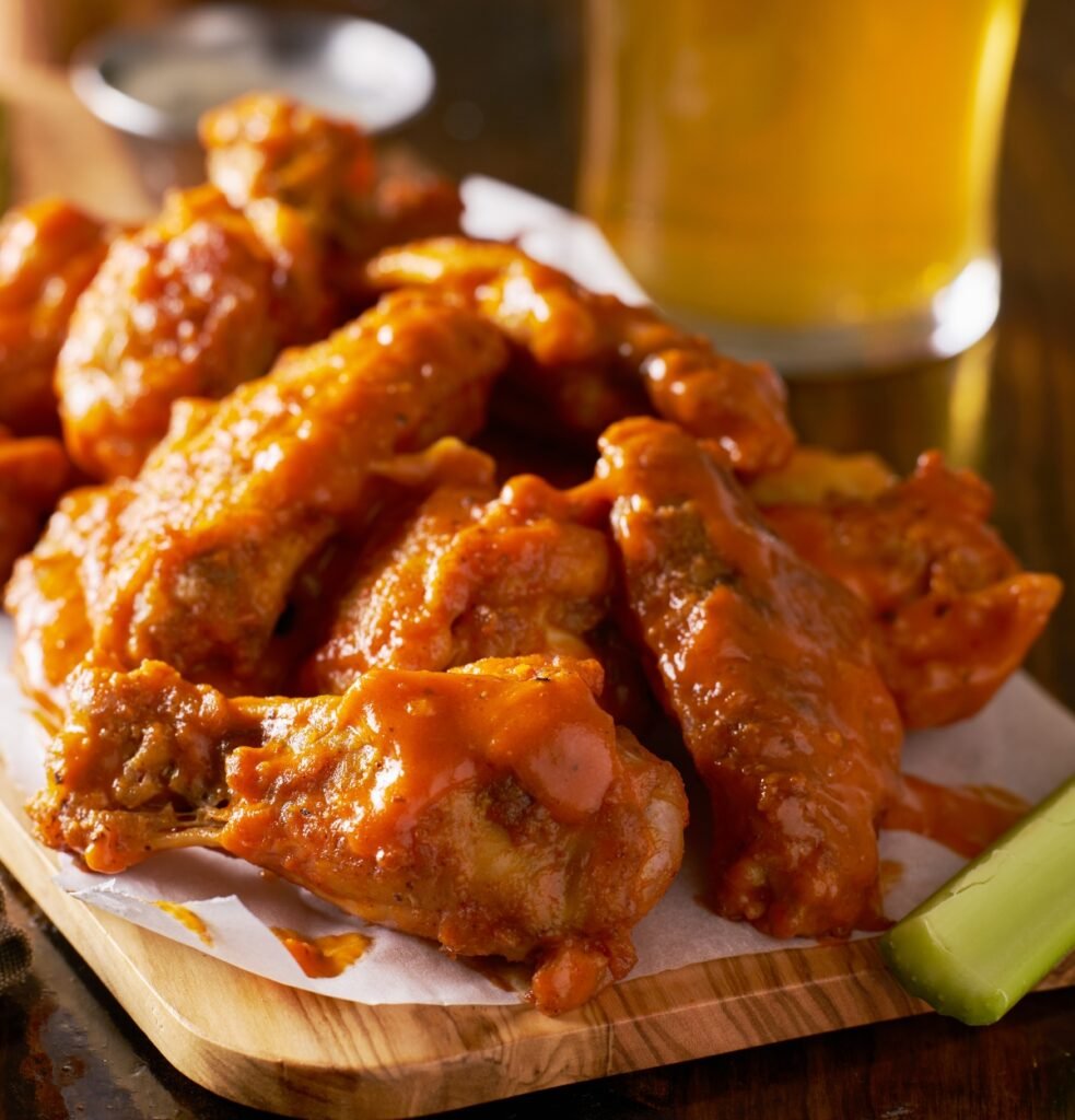 Atlanta's Best Wings, Sauced Buffalo Chicken Wings on Wooden Board with Celery Image by Joshua Resnick